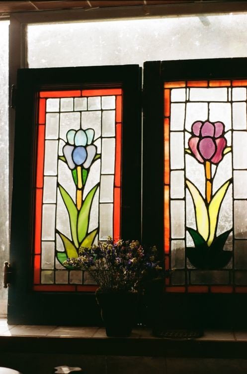 Colorful finished stained glass window with a vibrant floral design, showing true light passing through cut colored glass.