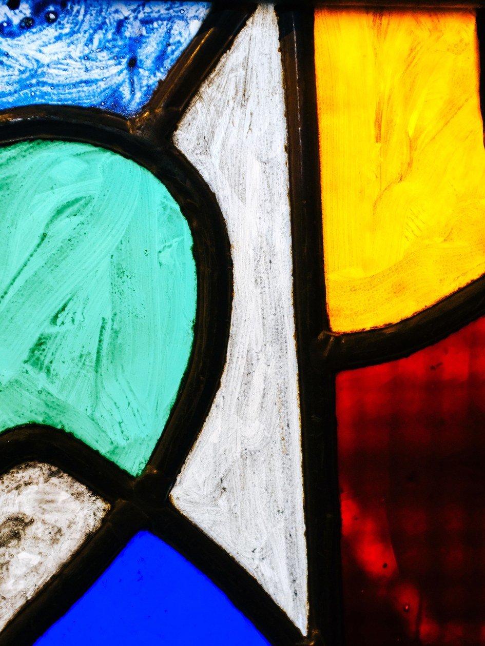 Close-up of a finished stained glass panel with clean, evenly soldered seams between the colored glass pieces.