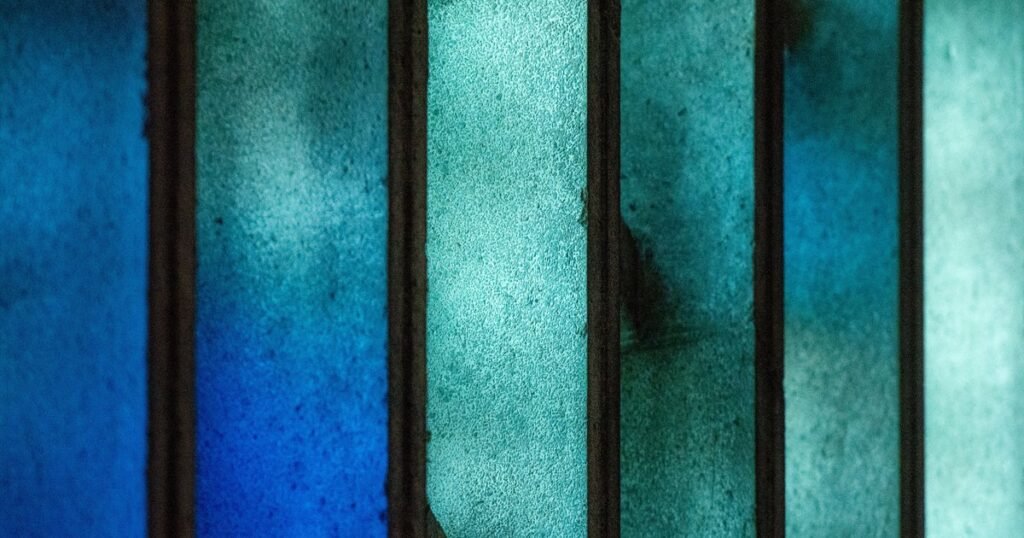 Close-up of an abstract blue stained glass window panel showing overlapping colored glass pieces and lead lines.