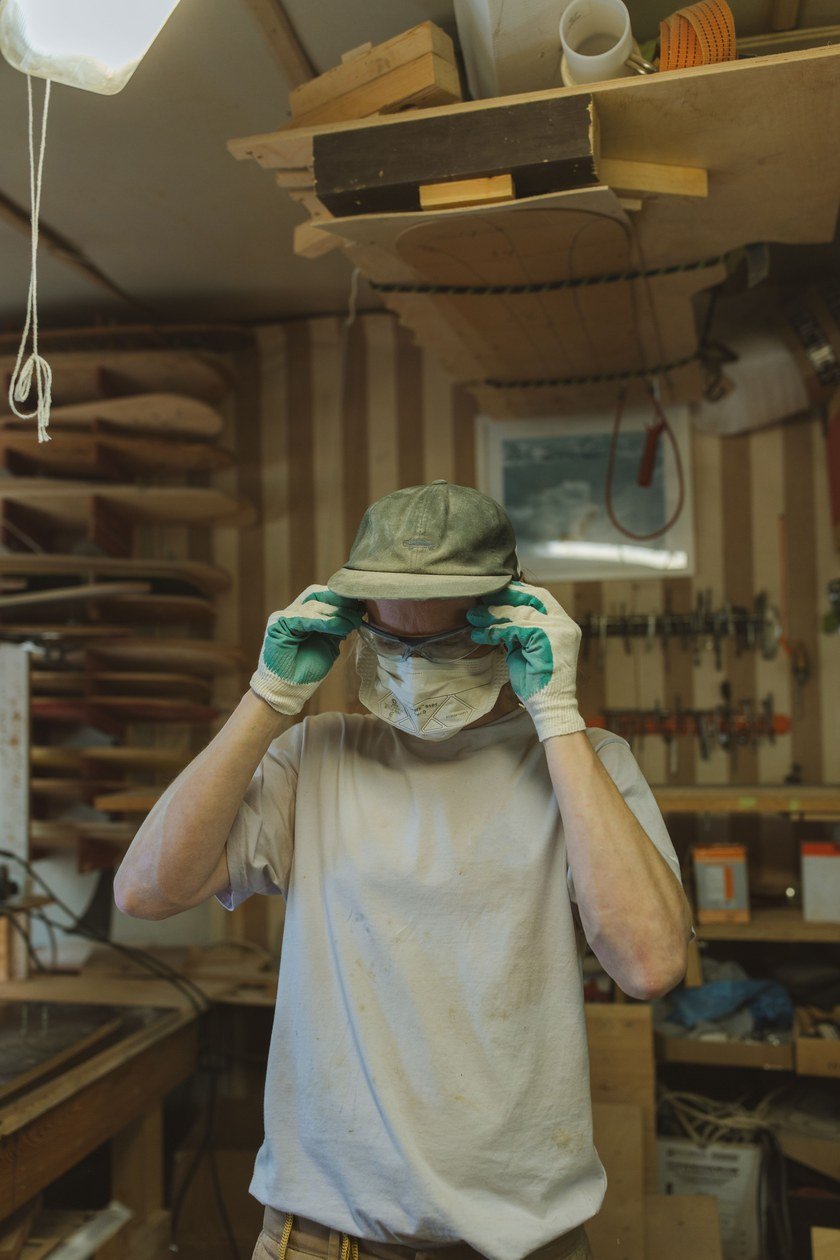 Craftsperson putting on safety glasses in a workshop, the same basic PPE habit worth building before picking up a hot soldering iron.